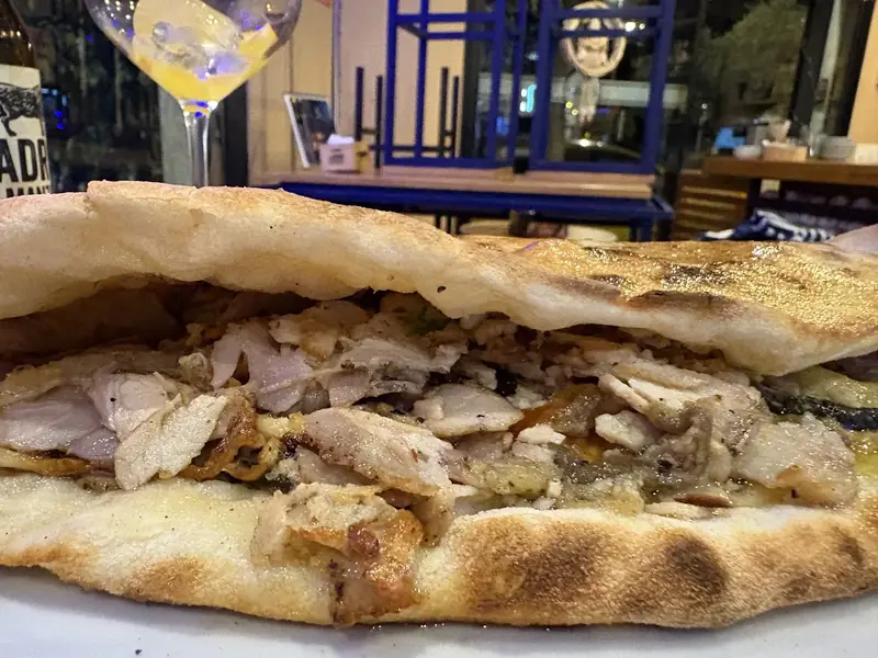 Panuozzo abierto relleno de porchetta, con el pan de masa de pizza dorado a la brasa